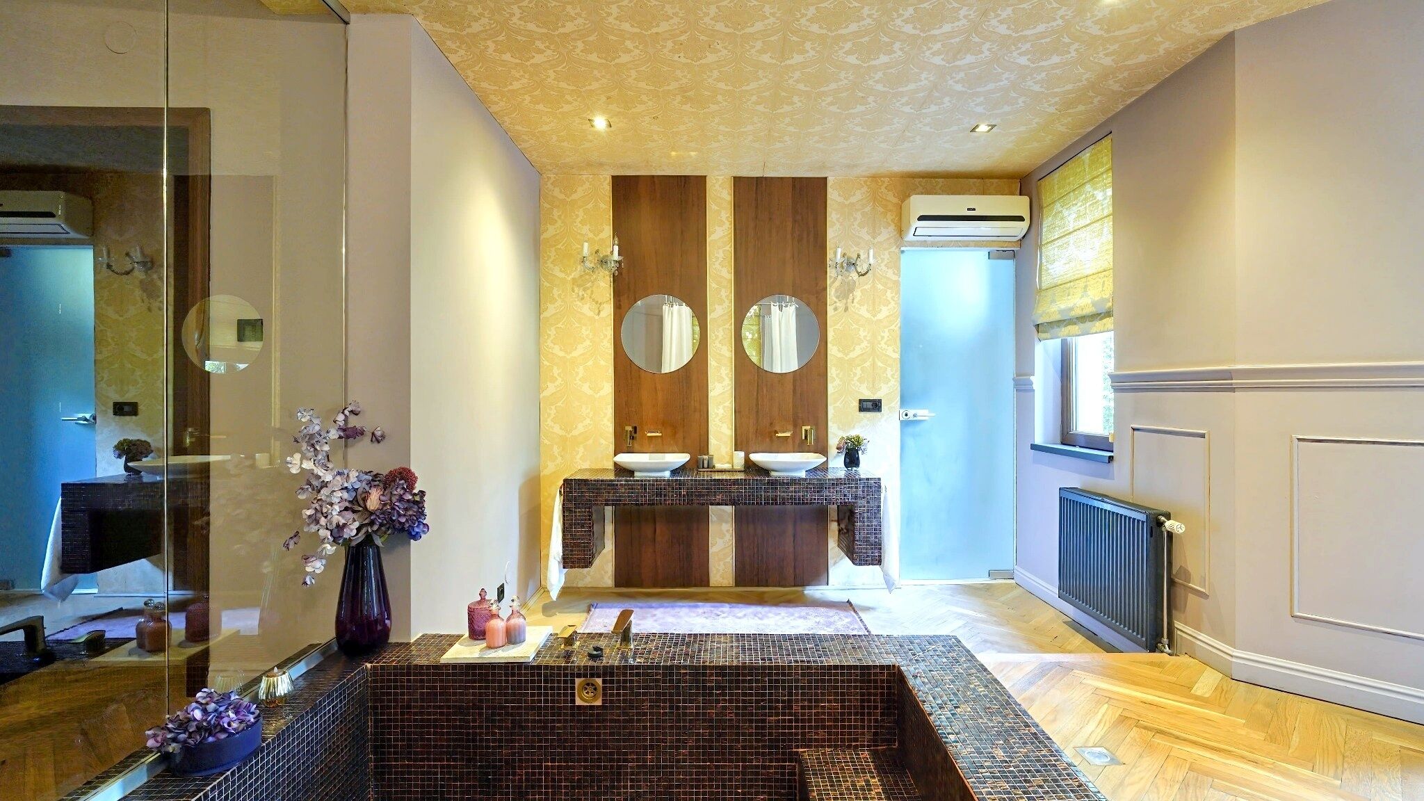 Un baño moderno con un espejo grande, dos lavamanos, una bañera independiente y una cabina de ducha de vidrio.