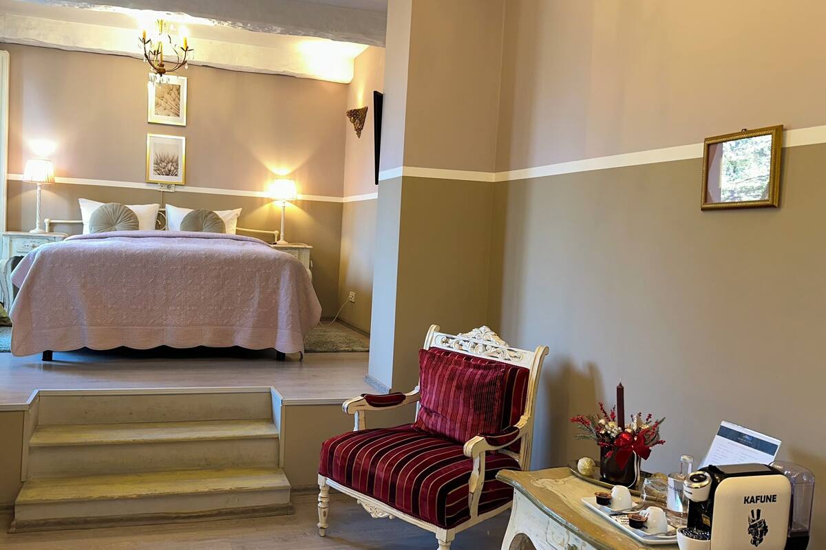 A hotel room with a bed, a chair, a coffee machine, and a desk.
