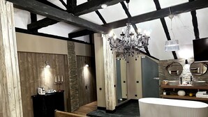 Ein Schlafzimmer mit einem großen Bett, einem Schminktisch mit Spiegel, einer Chandelier und Holzbalken.