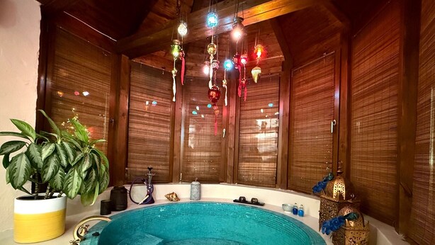 Ein Wellnessraum mit einer runden Whirlwanne, Holzwänden und dekorativer Beleuchtung.