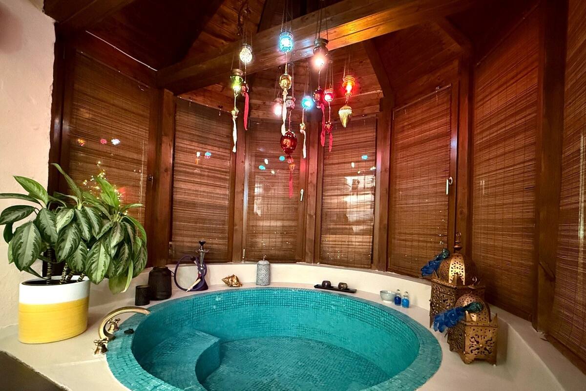 A spa room with a circular hot tub, wooden walls, and hanging decorative lights.