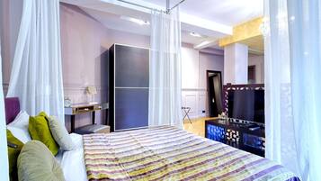 A bedroom with a bed, a vanity, a television, and a wardrobe.
