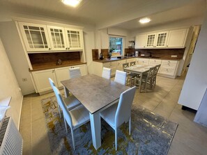 A modern kitchen with white cabinetry, a dining table with chairs, and a kitchen island. - North Sea dream Horumersiel - 120 m² apartment | garden & fireplace | 800 m to the beach (Wangerland)