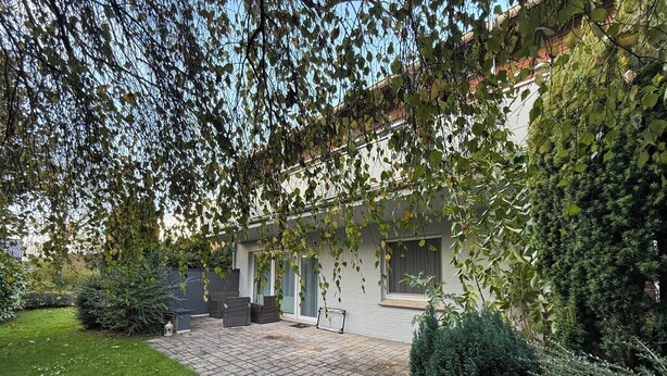 Ein modernes Haus mit Terrasse, Rasen und Garten.