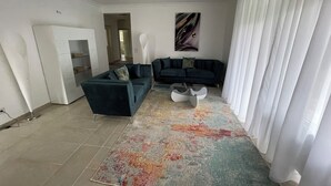 Ein modernes Wohnzimmer mit einem dunkelgrauen Sofa, einem weißen Couchtisch und einem farbenfrohen Teppich.