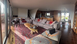 A spacious living room with a large sofa, a coffee table, and a dog. - Rustic villa vacation rental near Mount Rainier with farm charm, (Enumclaw)