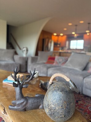 Una sala de estar con una mesa de centro, una figurita decorativa de ciervo y una jarra de piedra.