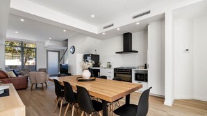 A modern kitchen with a wooden dining table, black chairs, and a black range hood. - Casa Tranquilla - Short Walk to North Coogee Beach (North Coogee)