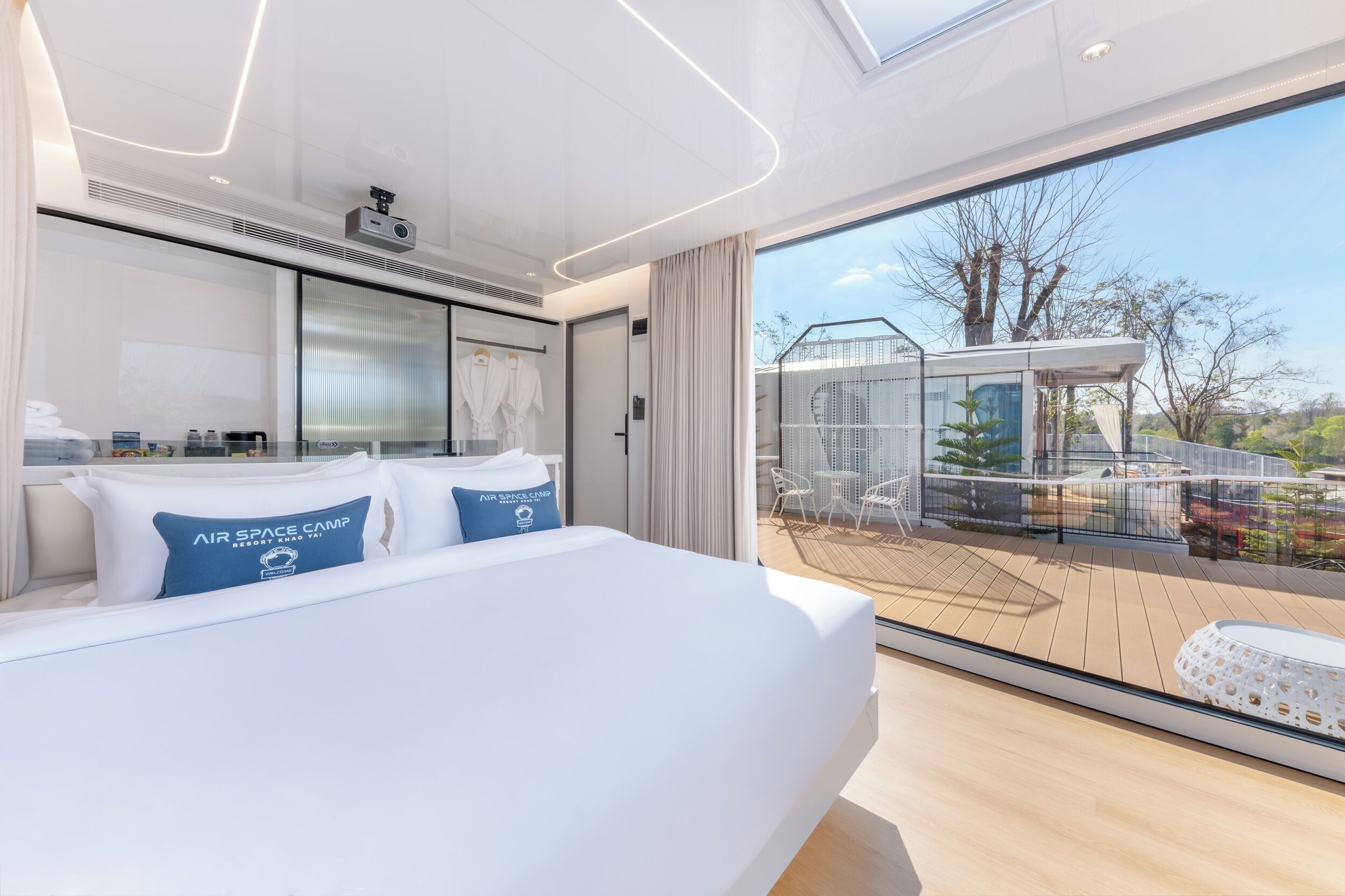 Una habitación de hotel moderna con una cama grande, un balcón con vistas al campo y una zona de ducha con paredes de vidrio.