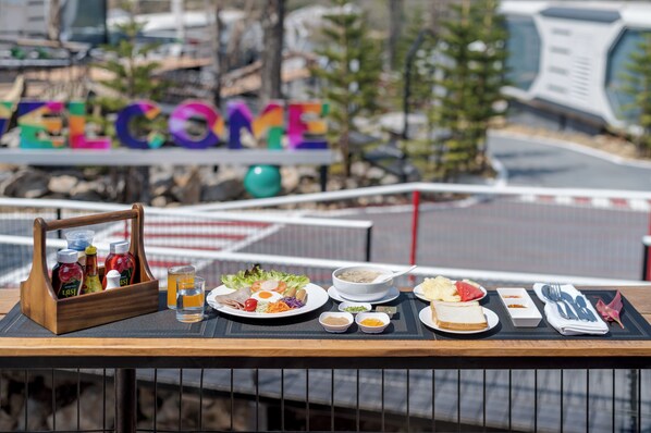 Una mesa con comida dispuesta, que incluye una bebida, ensalada y pan, con un letrero que dice 'WELCOME' al fondo.