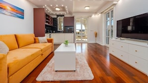 Uma sala de estar moderna com sofá, mesa de centro, televisão e área de cozinha.