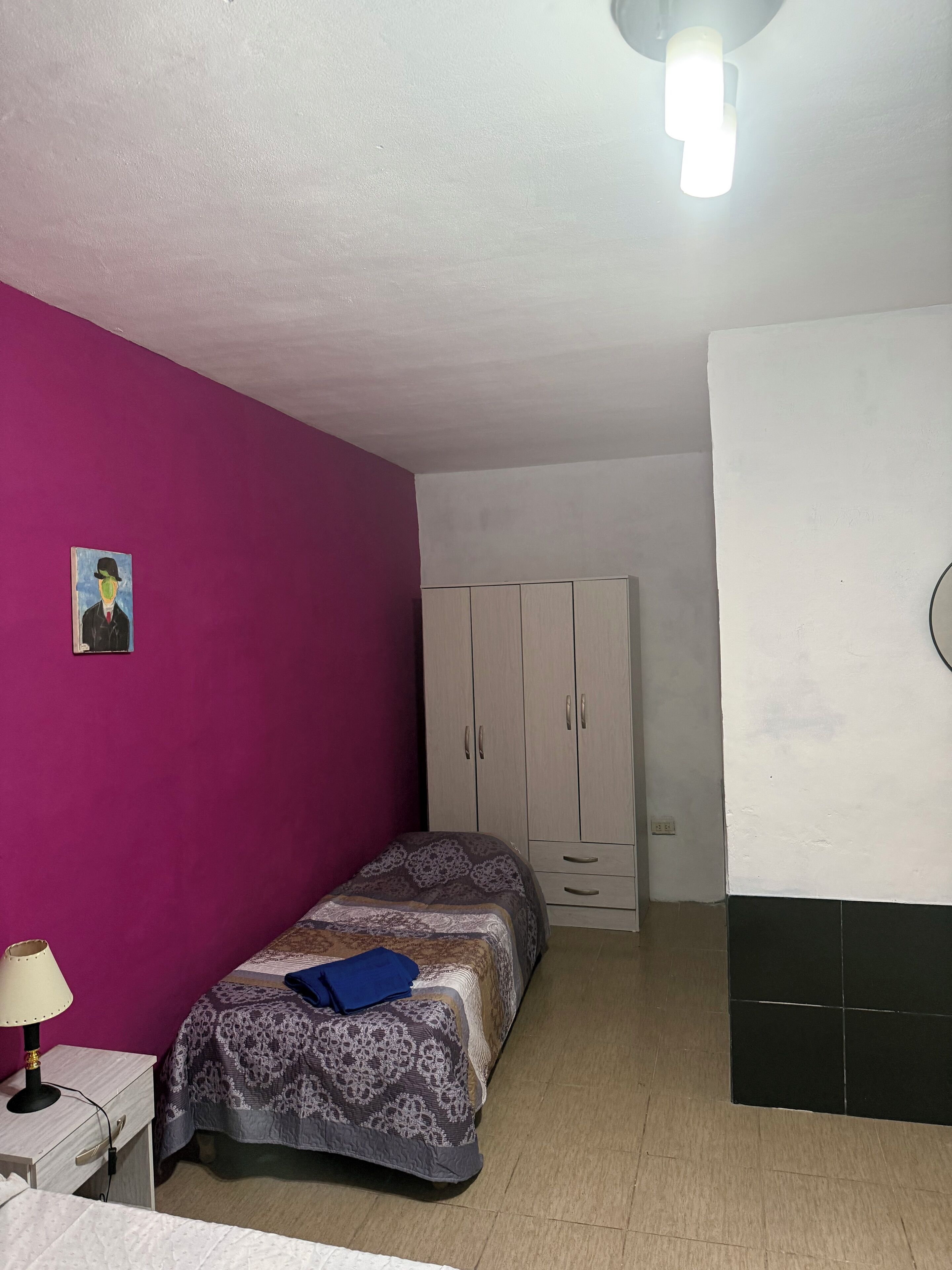 Un dormitorio con dos camas, un armario, un escritorio y una lámpara.