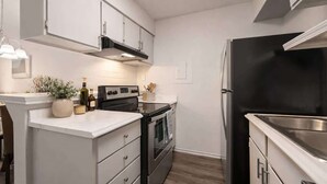 Eine moderne Küche mit weißen Schränken, einem schwarzen Kühlschrank und einem eingebauten Backofen.