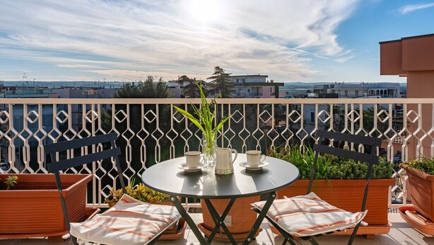 Un balcón con mesa y sillas, vistas de la ciudad y una barandilla decorativa.