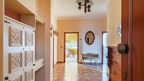 Un pasillo con puertas ornamentales, un banco y un espejo en la pared.