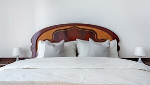 Una cama bien hecha con cabecera de madera, ropa de cama blanca y dos lámparas de noche.