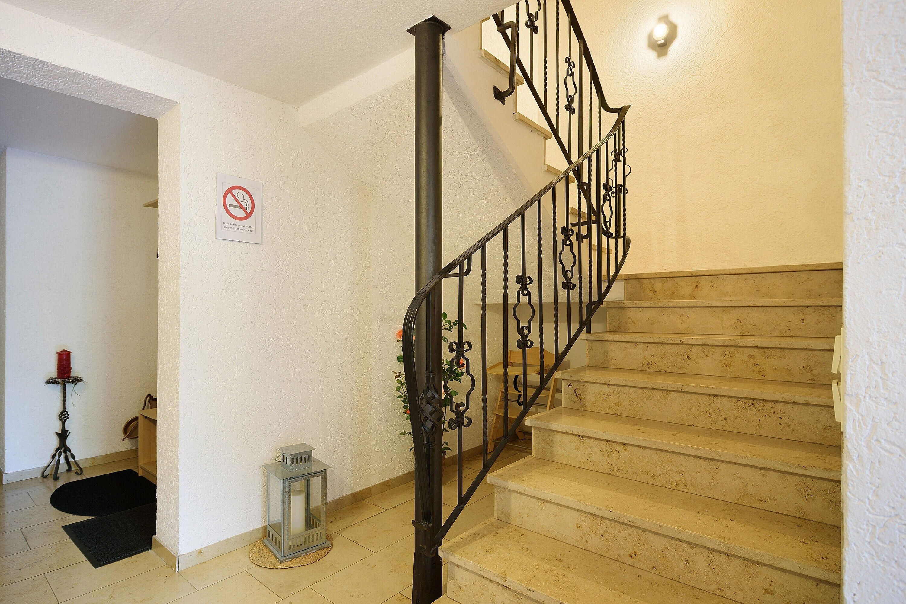 Una escalera con prohibición de fumar, una lámpara y una alfombra pequeña.