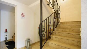 Una escalera con prohibición de fumar, una lámpara y una alfombra pequeña.