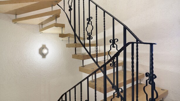 Una escalera con escalones de madera y barandillas de metal negro.