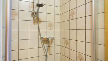 Eine Dusche mit Handbrause und verstellbaren Bedienelementen an der Wand.