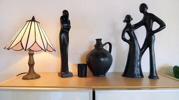 A table with a lamp, two black sculptures, and a black vase.