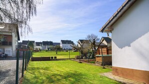 Una zona residencial con un césped cuidado, una valla de madera y casas con balcones y ventanas visibles.