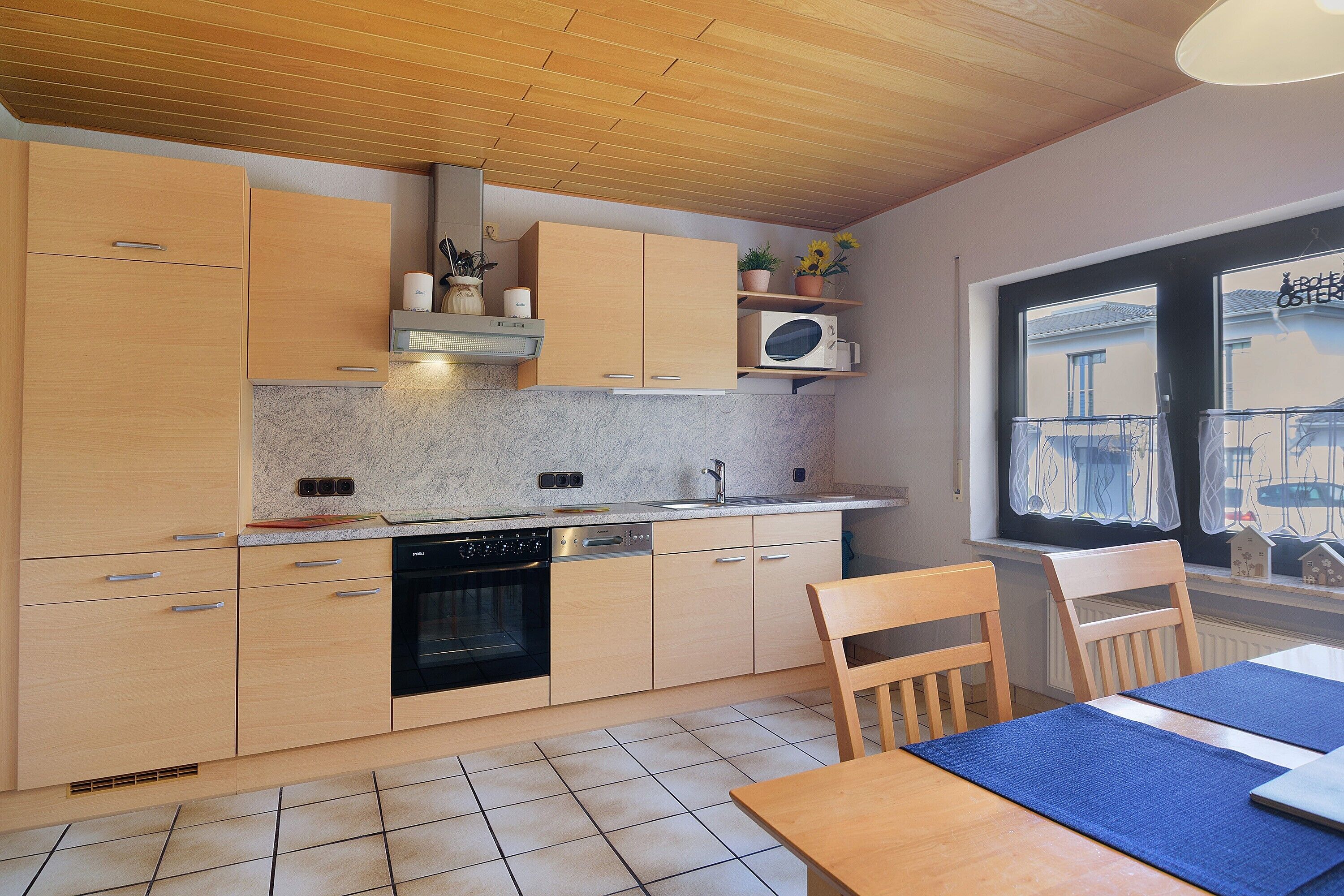 A kitchen with wooden cabinets, a dishwasher, and a window with a view of buildings.