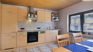 A kitchen with wooden cabinets, a dishwasher, and a window with a view of buildings.