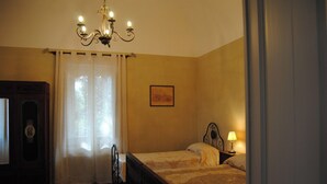 Ein Schlafzimmer mit zwei Betten, einer Kristallleuchtre, einem gerahmten Bild an der Wand und einem Fenster mit Vorhängen.