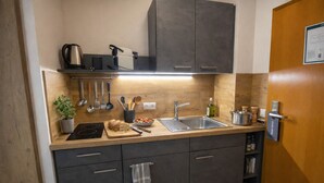 Cozinha moderna com bancada de madeira, pia de aço inoxidável e armários escuros.
