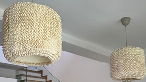 En modern trappa med trästeg och glasräcken, som leder upp till ett köksområde med ett matbord och stolar.