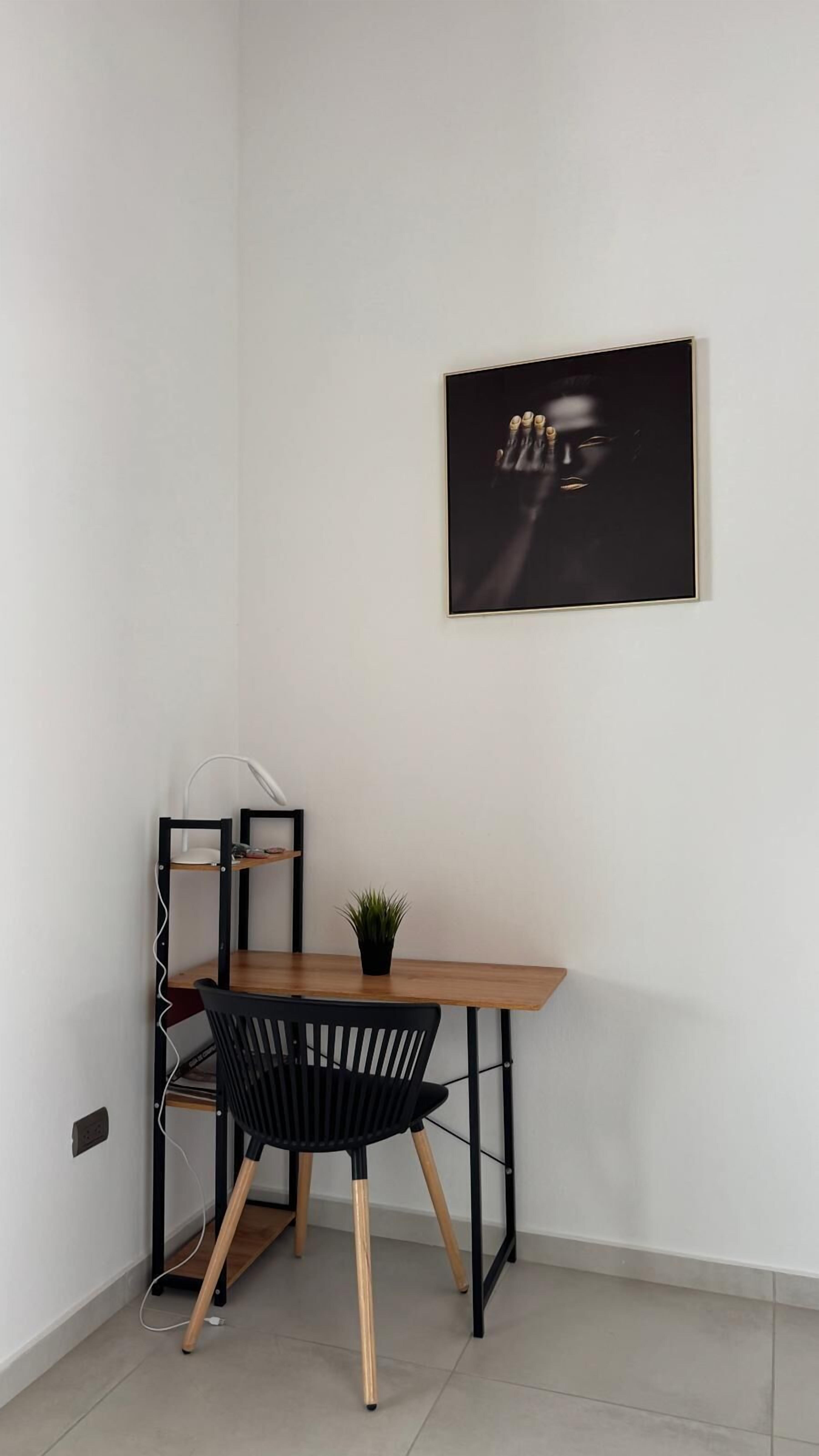 Un espace de travail aménagé dans un coin, avec un bureau, une chaise et un tableau encadré accroché au mur.