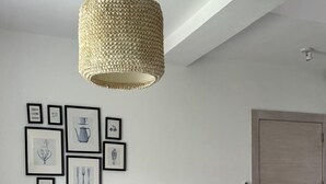 Ett modernt vardagsrum med en grå soffa, ett soffbord i trä och en hängande lampa med flätad skärm.