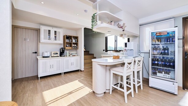 Une cuisine moderne avec des meubles blancs, un îlot central, une machine à café et un distributeur de boissons.