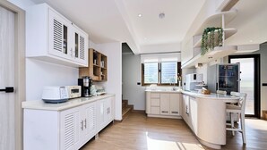 Une cuisine moderne avec des meubles blancs, un four à micro-ondes encastré et une machine à café.