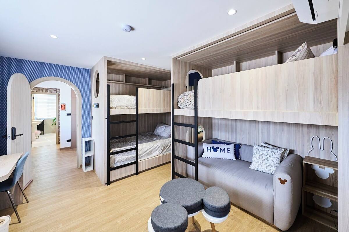 Une chambre moderne et compacte, équipée de lits superposés, d’un canapé et d’une petite table.