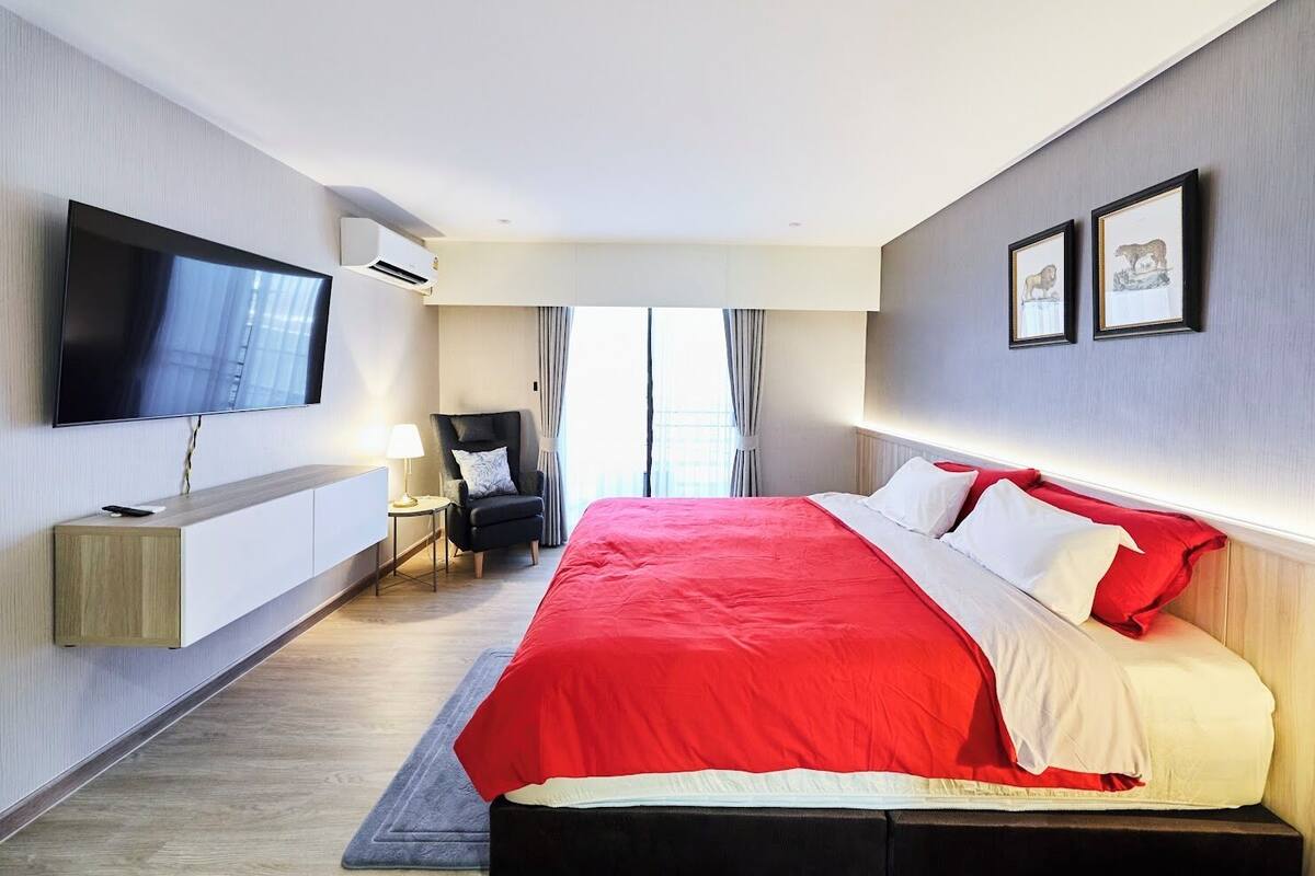 Une chambre d’hôtel avec un grand lit, une télévision, une chaise et un bureau.