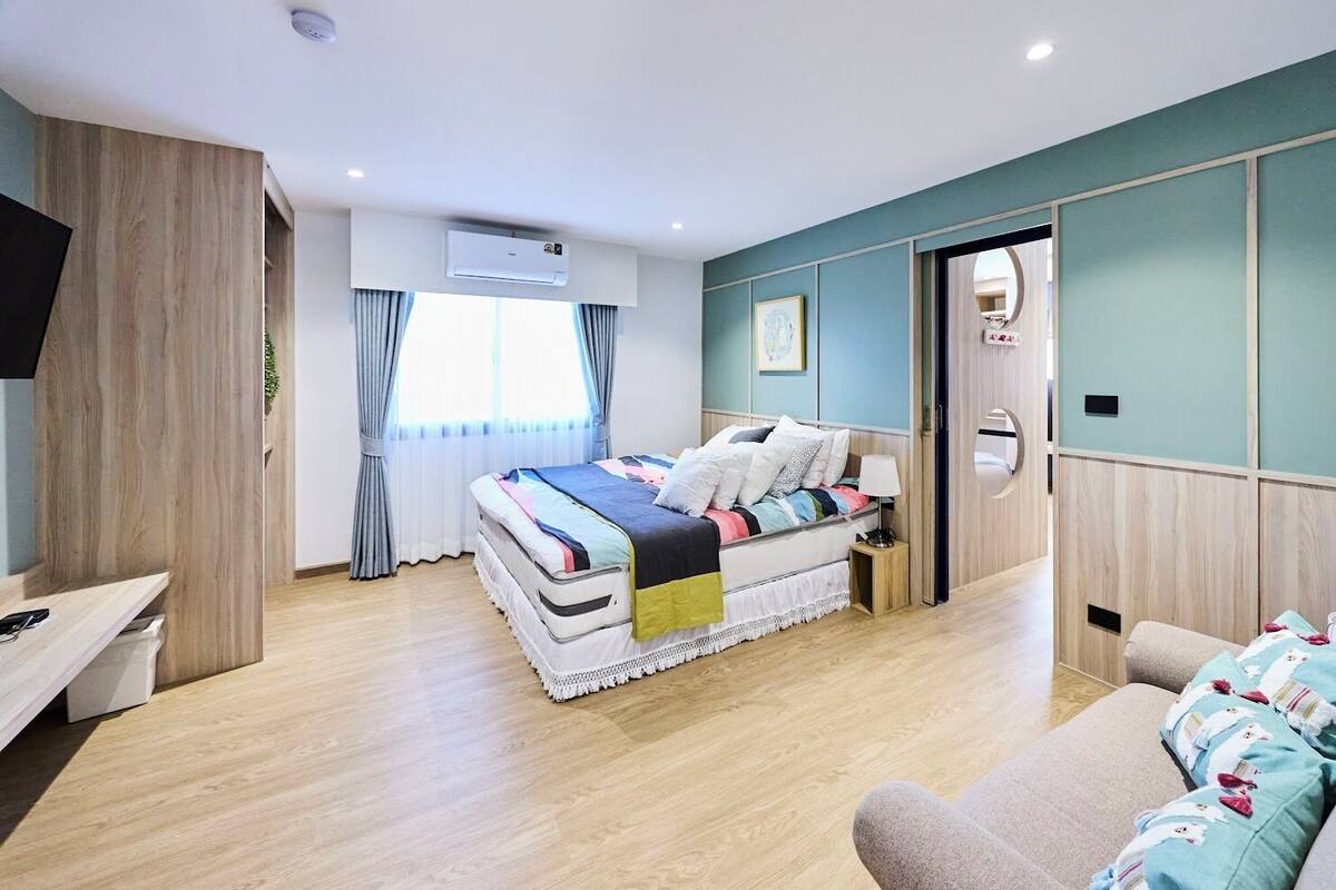 Une chambre à coucher avec un lit, une table de chevet, une lampe et une vue sur l’extérieur.