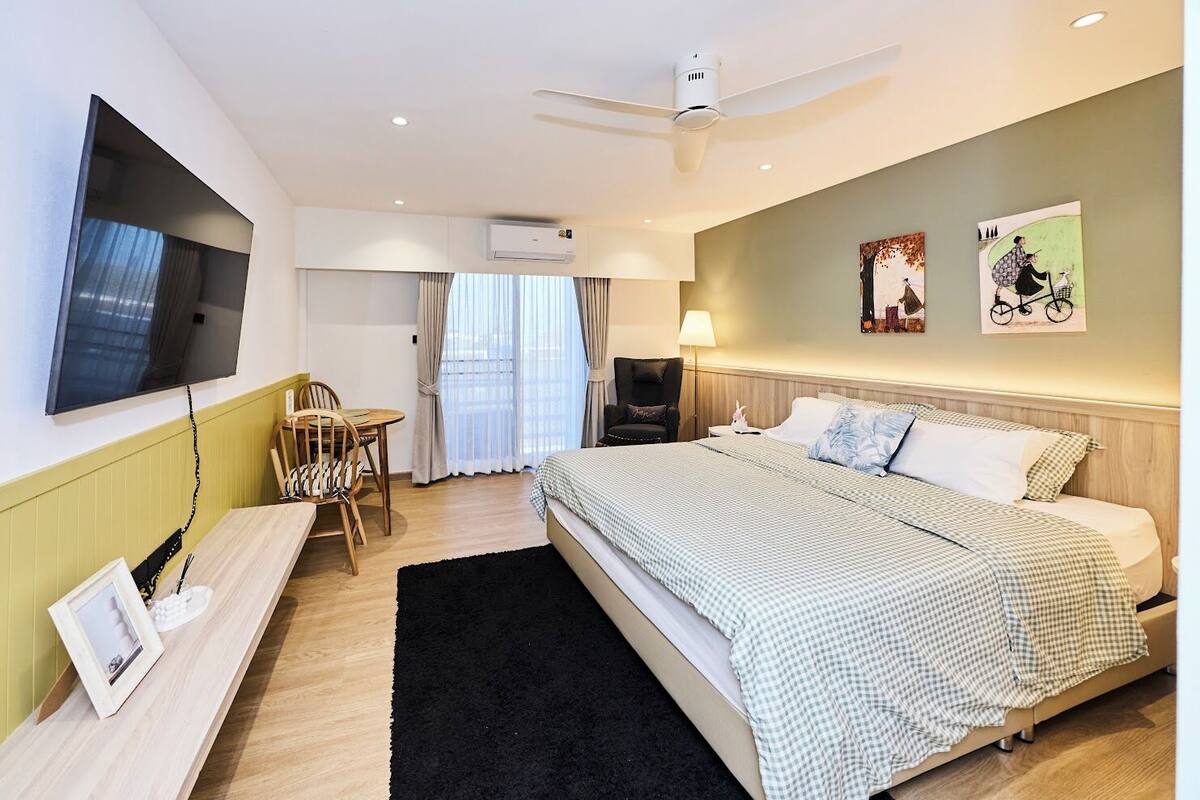 Une chambre d’hôtel moderne équipée d’un lit, d’un bureau, d’une chaise, d’une télévision et ornée d’œuvres d’art sur les murs.