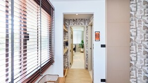 Un couloir avec une fenêtre, un panier, une porte et un mur orné de motifs.