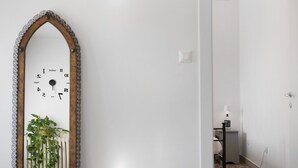A hallway with a wall-mounted clock, a potted plant, and a door leading to another room. - Apartment 'Ca' Mirabello' with Wi-Fi and Air Conditioning (Bardolino)