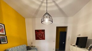 Un soggiorno con un divano, una TV su un mobile bianco e una lampada a soffitto.