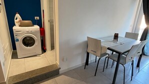 Una cucina moderna con lavatrice integrata, un tavolo da pranzo con sedie e una finestra con tende.