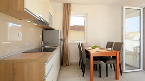 Een moderne keuken met een eethoek, inclusief een tafel met stoelen, een raam met gordijnen en een schuifdeur van glas.