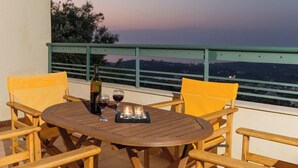 A wooden table with two chairs on a balcony, a bottle of wine, and two glasses. - Alkistis Villa with amazing sea view (Rethymno)