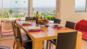 A dining area with a table set for two, a bottle of wine, and a basket of fruit. - Alkistis Villa with amazing sea view (Rethymno)