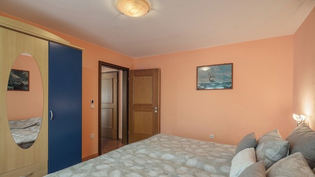 Une chambre à coucher avec un lit, une armoire, une porte et un tableau au mur.