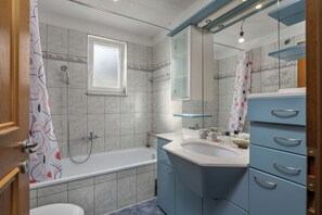 Ein Badezimmer mit Badewanne, Dusche, Waschbecken und Spiegel.