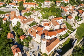 Vista aérea de un pueblo histórico con edificios muy juntos, calles estrechas y una iglesia destacada con un campanario.