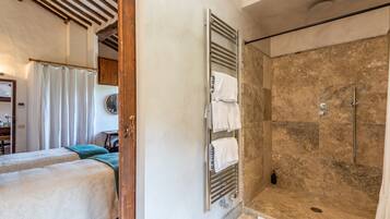 A bathroom with a shower, a toilet, and a towel rack.